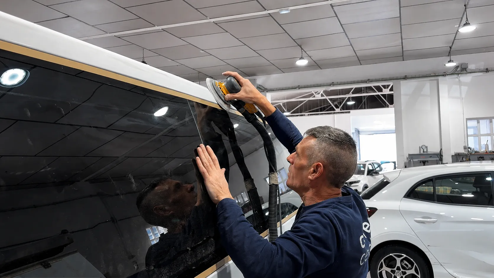 Mecánico de Carreras Center puliendo la carrocería de un coche en el taller