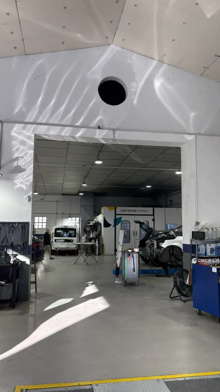 Nave del taller de Carreras Center en Maó, con coches en los elevadores